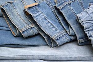 Lots of jeans pants in a stack. Denim background. photo