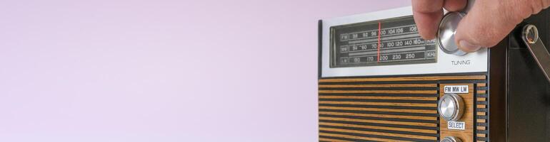 Authentic 70s radio receiver. Front view. On pink background. banner photo