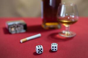still life - whiskey, cigarettes, dice. red table, brown background photo