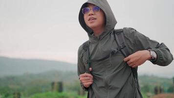 Man with backpack looking into the distance while hiking in the mountains in summer Spread your hands out to express happiness and relaxation video