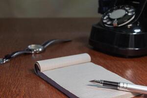 still life - old telephone, notebook, ink pen, wristwatch. copy space photo