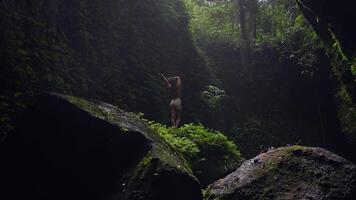 girl stands on a stone in a jungle cave with sun rays and light fog video