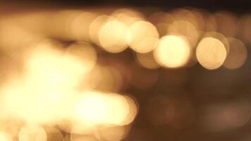 Abstract sea summer ocean sunset nature bokeh background. Small waves on azure water surface in motion blur with golden bokeh lights from sun. Holiday, vacation and recreational concept. Slow motion video