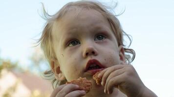 blonde, curly-headed child savors a cookie with a captivated,distant stare, charming representation of unbridled imagination video