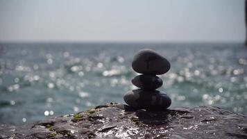 Balanced pebble pyramid on the beach on a sunny day. Abstract Sea bokeh on the background. Selective focus. Zen stones on the sea beach, meditation, spa, harmony, calmness, balance concept video