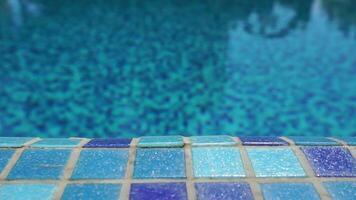 Pool water background with wavy clear fresh water. Calm rest on sunny day. Abstract reflections on the surface of the water with texture of bright blue pool tiles. Turquoise water surface. Slow motion video