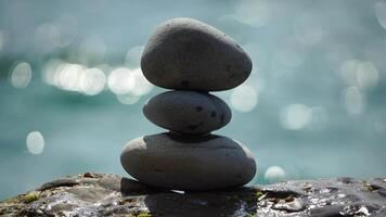 Balanced pebble pyramid on the beach on a sunny day. Abstract Sea bokeh on the background. Selective focus. Zen stones on the sea beach, meditation, spa, harmony, calmness, balance concept video