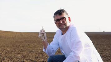 Laboratory worker holding professional glassware and testing black soil before harvest in the field. Assessment soil contamination with toxic substances. Selection fertilizers video