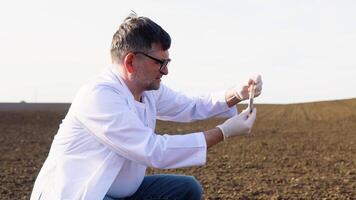 Laboratory worker holding professional glassware and testing black soil before harvest in the field. Assessment soil contamination with toxic substances. Selection fertilizers video
