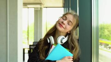 Portrait of dreamy girl student with books in hands in the university building. Back to school video