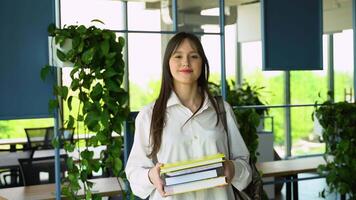 Portrait of an college girl student with books in hands in the university building. Back to school video