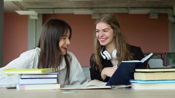 Two students doing homework together and helping each other sitting in a table at university. Preparing to the exams video