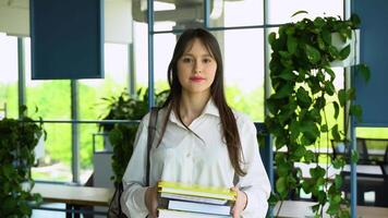 Portrait of an college girl student with books in hands in the university building. Back to school video