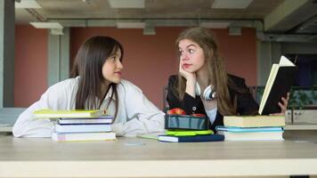 Two students doing homework together and helping each other sitting in a table at university. Preparing to the exams video