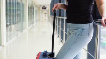 Woman with suitcase in airport hallway, close up video