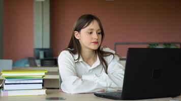 focado menina usando computador portátil dentro aula, atraente fêmea aluna Aprendendo linguagem, assistindo conectados webinário, ouvindo audio curso, e-learning Educação conceito video
