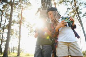 Two happy children having fun during forest hike on beautiful day in pine forest. Cute boy scout with binoculars during hiking in summer forest. Concepts of adventure, scouting and hiking tourism photo