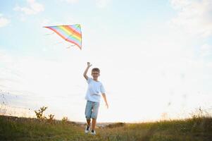 Boy is running with a kite during the day in the field photo