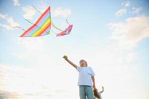 Boy is running with a kite during the day in the field photo