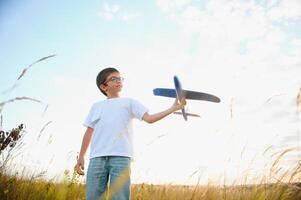 Happy kid playing with toy airplane against blue summer sky background. photo