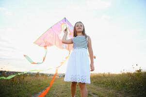 happy child girl with a kite running on meadow in summer in nature photo