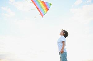 Boy is running with a kite during the day in the field photo