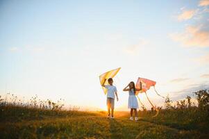 Happy children launch a kite in the field at sunset. Little boy and girl on summer vacation. photo