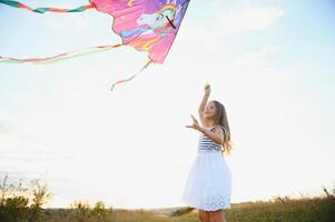 one happy little girl running on field with kite. photo