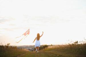 one happy little girl running on field with kite. photo