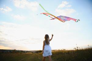 one happy little girl running on field with kite. photo