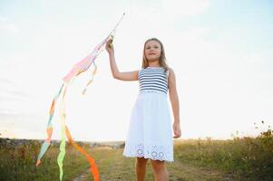 one happy little girl running on field with kite. photo
