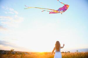happy child girl with a kite running on meadow in summer in nature photo