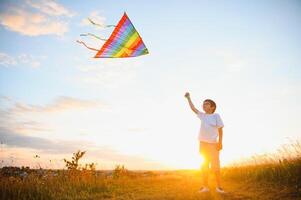 Boy is running with a kite during the day in the field photo