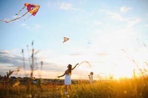 Children launch a kite in the field at sunset photo