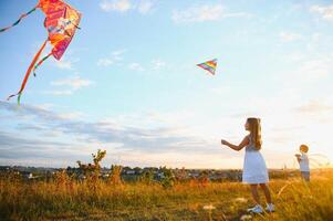 Children launch a kite in the field at sunset photo