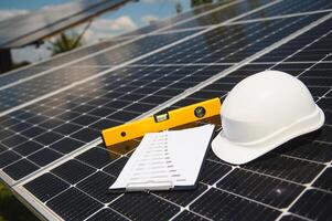 Solar cell contractor document with orange engineering team helmet on solar cells panels. Renewable energy and ecology concept. photo