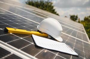 Solar cell contractor document with orange engineering team helmet on solar cells panels. Renewable energy and ecology concept. photo