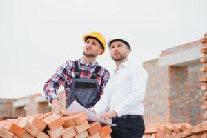 engineer and builder in hard hats discussing blueprint on construction site. photo