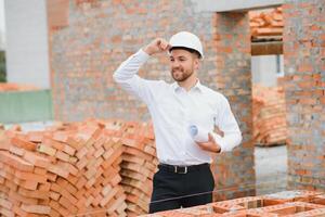Engineering Consulting People on construction site holding blueprint in his hand. Building inspector. Construction site check drawing and business workflow of new building. photo