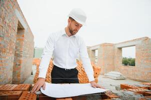 Engineering Consulting People on construction site holding blueprint in his hand. Building inspector. Construction site check drawing and business workflow of new building. photo