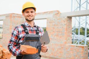 Installing brick wall. Construction worker in uniform and safety equipment have job on building photo