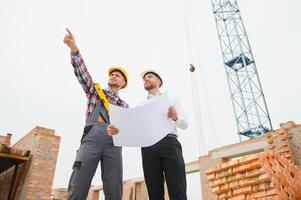construcción ingenieros supervisando Progreso de construcción proyecto estar en nuevo hormigón piso parte superior techo y grua antecedentes. foto