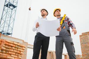 construcción ingenieros supervisando Progreso de construcción proyecto estar en nuevo hormigón piso parte superior techo y grua antecedentes. foto