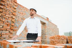 Architect at a construction site with blueprints photo