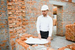 Engineering Consulting People on construction site holding blueprint in his hand. Building inspector. Construction site check drawing and business workflow of new building. photo