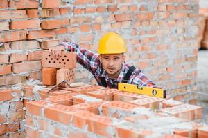 Construction worker man in work clothes and a construction helmet. Portrait of positive male builder in hardhat working at construction site. photo