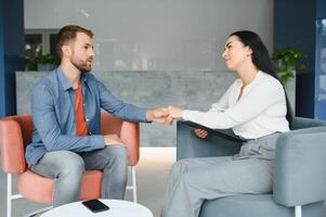 Psychologist talking with patient on therapy session. Depressed man speaking to a therapist while she is taking notes. photo