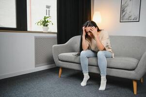 Depressed sad attractive woman crying on sofa couch at home feeling lonely tired and worried suffering depression in mental health, loneliness and isolation concept. Psychology, solitude and people. photo