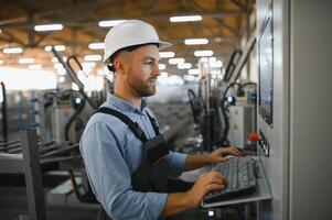 Operator wearing safety hat behind control panel on a factory photo