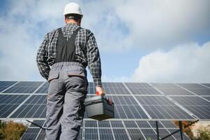 Professional worker installing solar panels on the metal construction, using different equipment, wearing helmet. Innovative solution for energy solving. Use renewable resources. Green energy. photo